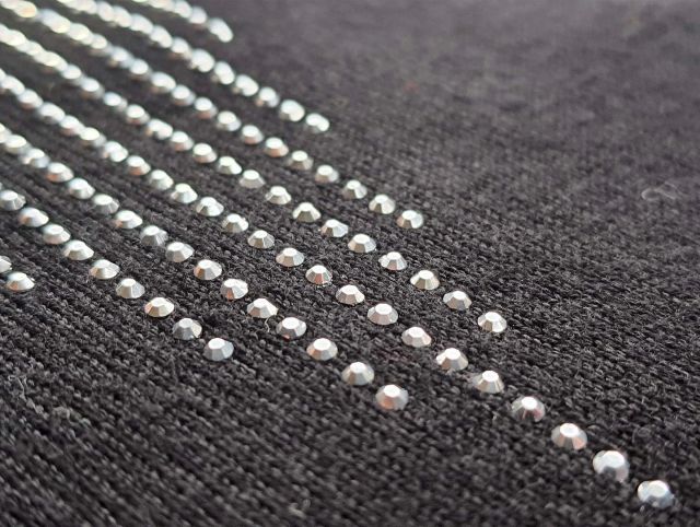 The hotfix technique has been used to transfer the silver studs onto this jersey fabric. The studs have adhesive on the underside and are supplied on a clear sheet, which is placed on the required area. The hotfix machine adds pressure and heat, to transfer the studs securely onto the fabric. #jersey #jerseyfabric #mytrainedeyejersey
