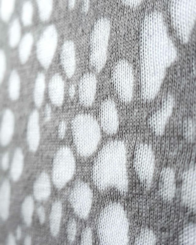 This pattern is created using the burn out technique. It is commonly done on a blend fabric, using
a synthetic man-made and natural fibre. A screen is cut with areas left open, where burn out is
required. A burn out paste is applied through the screen onto the exposed areas. This eats away
at the natural fibres, which are grey, exposing the white man-made yarn.  #mytrainedeye #burnoutjersey #patternedfabric #burnout #jersey