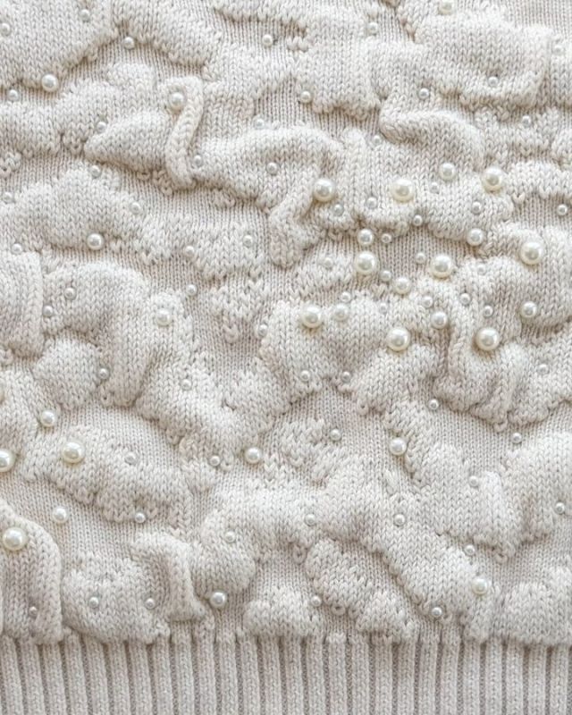 The pearls on this @zara knit have been attached by a device that punches a metal clasp from the back of
the fabric through to the front, piercing the plastic bead and holding it in place. This process is done after
knitting shaped panels but before makeup.
#mytrainedeye #zara #embellishedknit #diamonteknits #texturedknits #knitwear